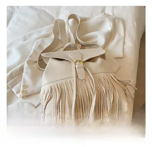 Détail du sac à dos beige en similicuir avec franges et boucle métallique dorée