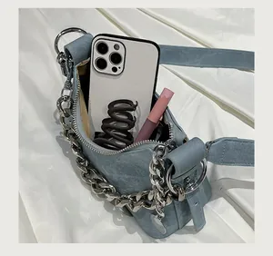 Détail du sac croissant en denim bleu clair montrant la capacité pour téléphone et maquillage