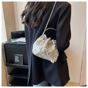 Detail of silver sequin bucket bag with round metal handle, chain strap and pearls