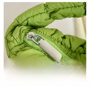 Detail of a smooth silver metal zipper on a grass green quilted puffer mini handbag