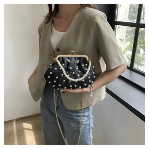 Détail d'un élégant sac de soirée noir plissé avec perles et chaîne dorée