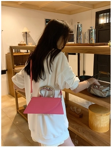 Detail of fuchsia geometric handbag with silver heart-shaped metal handle and shoulder strap