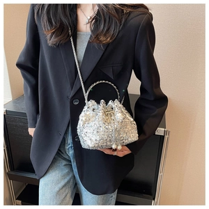 Silver sequin bucket bag with metal ring handle and pearl pendant on a model
