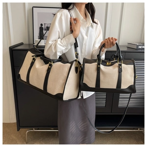 Detail of canvas travel bag set with black leather straps and gold-tone hardware on model