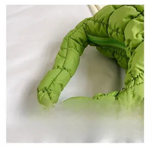 Detail of green quilted cloud bag featuring padded handle and color-matched zipper closure