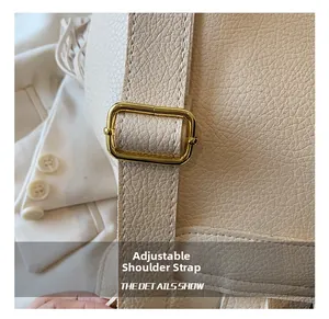 Détail de la bandoulière réglable sur sac à dos en similicuir crème avec boucle dorée