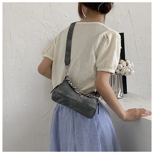 Détail du sac bandoulière en daim gris avec chaîne argentée et large sangle