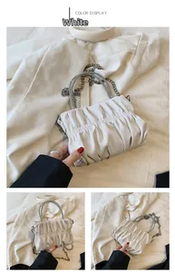 Detail of white pleated cloud bag with sparkling rhinestone and metal chain straps