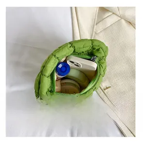 Internal view of green quilted cloud bag showing phone and cosmetic storage capacity