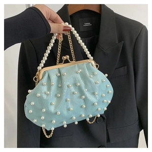 Détail d'un sac à main bleu clair perlé avec fermoir doré et doubles chaînes