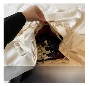 Détail montrant l'intérieur spacieux du sac à main seau blanc en cuir avec des glands