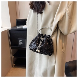 Detail of black sequined bucket bag with silver ring handle and pearl drawstring charms