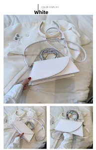Detail view of white trapezoid handbag with silver heart handle and removable strap
