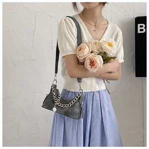 Sac croissant gris foncé à texture marbrée avec chaîne argentée porté par un modèle
