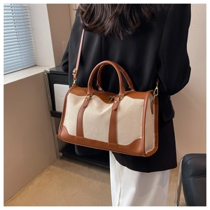 Detail showing the brown leather handles and beige canvas of the Boston tote bag