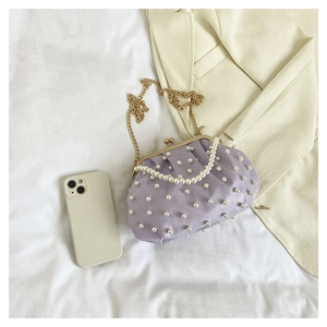 Détail du sac à main plissé violet clair avec perles blanches et bandoulière dorée
