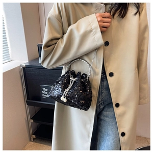 Detail of black sequin bucket bag featuring drawstring closure and pearl accents