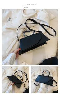 Detail of black asymmetric crossbody bag with silver fluid-metal top handle and matte PU strap