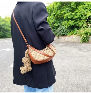 Détail du sac demi-lune avec imprimé monogramme marron et charmant pendentif en forme d'ours