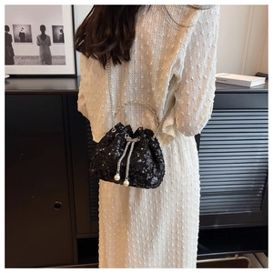 Model view of black sequin bucket bag with silver ring handle and pearl drawstrings