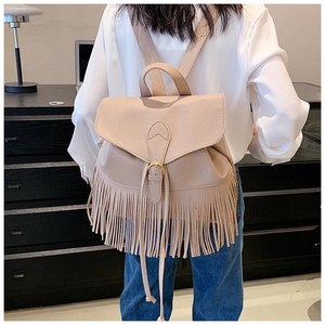 Détail d'un sac à dos beige en similicuir avec longues franges et boucle dorée