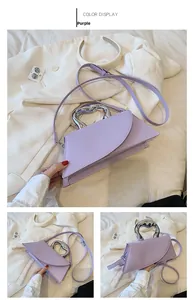 Detail view of purple envelope bag with silver heart-shaped metal handle and strap