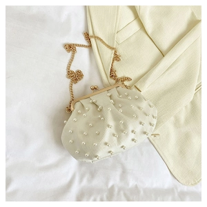 Détail du sac à main crème élégant avec décorations en perles et bandoulière dorée