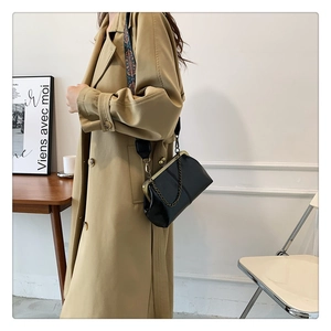 Detail of black shell bag with jacquard strap and retro metal frame on model