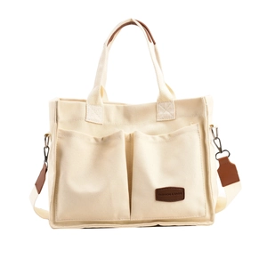 Cream canvas tote bag with dual front pockets and brown leather patch, front view