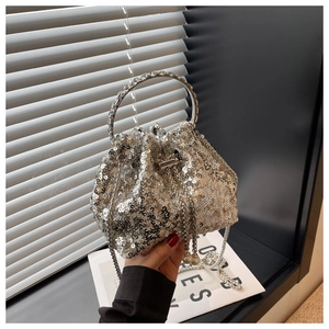 Close-up of silver sequin bucket bag featuring pearl drawstring and metal ring handle