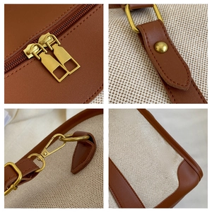 Detail view of canvas tote featuring gold dual zippers and reinforced leather corners