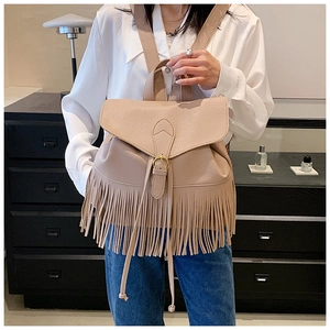 Détail d'un sac à dos beige à longues franges et boucle en métal doré en similicuir