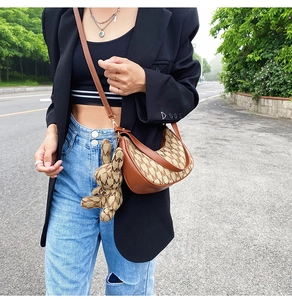 Détail du sac croissant marron avec motif lettre M et charm lapin mignon attaché