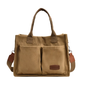 Detail view of brown canvas tote bag with front utility pockets and adjustable shoulder strap