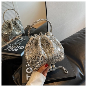 Detailed shot of a silver sequined bucket bag with metal ring handle and pearl drawstrings