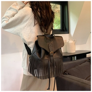 Vue détaillée du sac à dos en cuir noir avec longues franges et boucle en métal doré