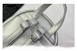 Detail of silver metallic backpack showing reinforced handle straps and metal buckles