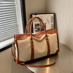 Large cream canvas and brown leather tote bag with a removable shoulder strap for travel