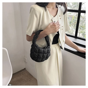 Detail of black quilted cloud handbag with textured crescent shape and soft material