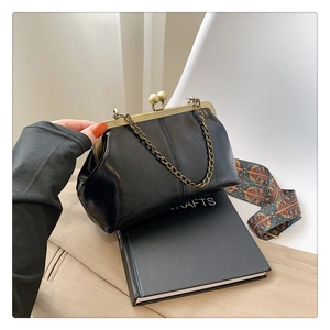 Detail of vintage black shell bag with glossy leather and colorful woven strap