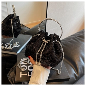 Macro shot of black sequin bucket bag with crystal ring handle and pearl drawstrings
