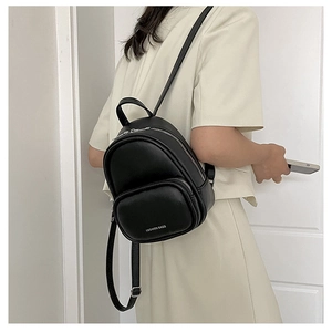 Detailed back view of a minimalist black mini leather backpack on a female model