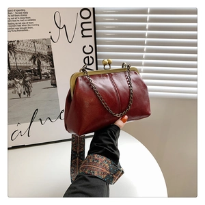 Detail of vintage red kiss-lock handbag with golden chain and ethnic woven shoulder strap