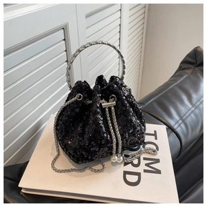 Close-up of black sequined bucket bag featuring silver metal handles and pearl drawstrings