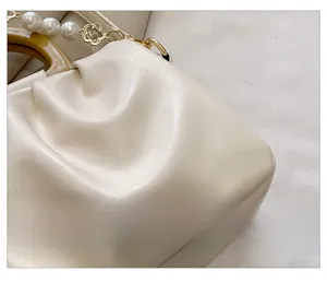 Détail du sac nuage plissé crème avec chaîne en perles et poignée ronde style bois