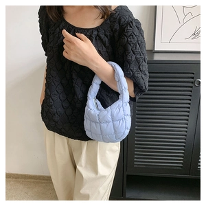 Close-up of light blue quilted cloud bag with puffy texture and integrated handle