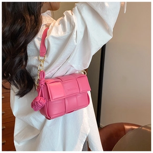 Détail d'un sac bandoulière rose matelassé avec chaîne dorée et breloque tressée
