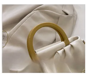 Détail du sac plissé blanc crème avec poignée en résine jaune et doublure rouge