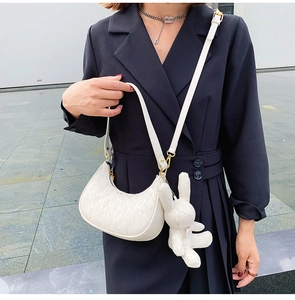 Détail du sac croissant crème avec motif M et un adorable pendentif en forme de lapin