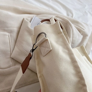 Chic beige canvas tote bag with metal hardware and leather accents in minimalist style